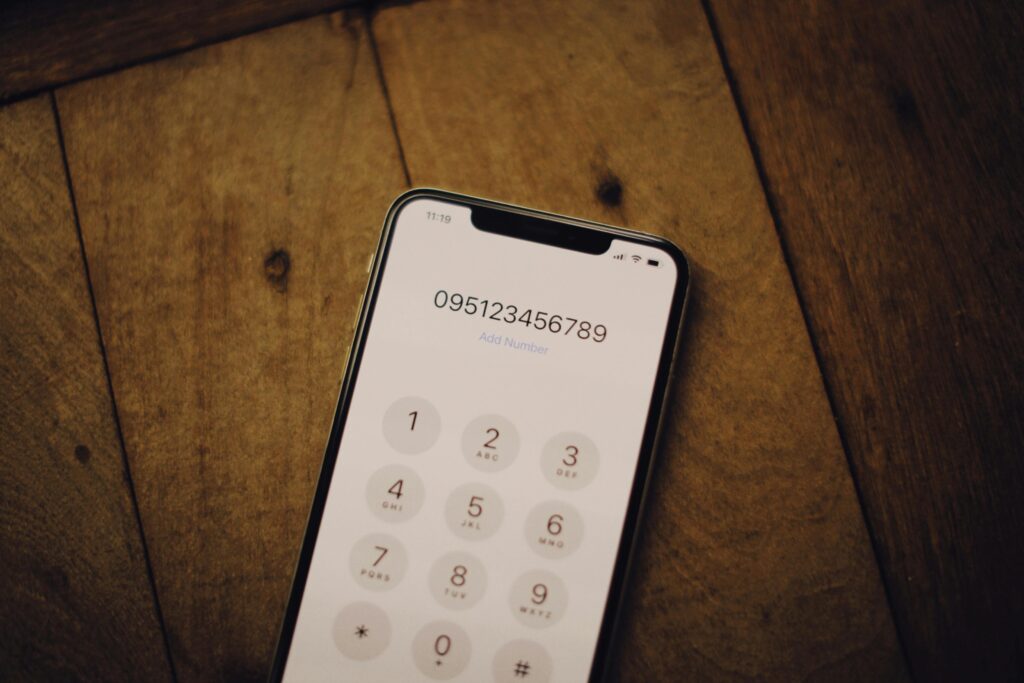 Close-up of a smartphone with a numeric dial pad placed on a wooden surface.